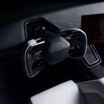 Interieur van de Tesla Roadster met een hoekig stuur bekleed met grijs alcantara, een liggend middenscherm met circuitkaart en rondetijden, en een witte kuipstoel.