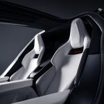 Twee witte kuipstoelen met rood verlicht Roadster-logo, gezien door de geopende deur onder het glazen dak van de Tesla Roadster.