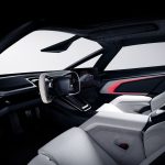 Dashboard van de Tesla Roadster met hoekig stuur, zwevend middenscherm met de auto in beeld, een grote voorruit en rode sfeerverlichting in het deurpaneel.