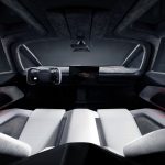Blik van achteren door het interieur van de Tesla Roadster naar het dashboard, met twee witte stoelen, een donkere alcantara hemel, het stuur en het middenscherm.