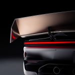 Detail van de grote achterspoiler van de Tesla Roadster met koperkleurige onderzijde, boven de doorlopende rode achterlichtbalk.