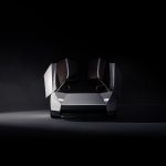 Vooraanzicht van de witte Tesla Roadster in een donkere studio, met beide deuren omhoog geopend en smalle ledkoplampen.