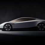 Zijaanzicht van de witte Tesla Roadster met lage, wigvormige lijn, getinte ruiten en stervormige velgen, in een donkere studio.