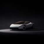 Witte Tesla Roadster schuin van voren in een donkere studio, met lichtbalk in de neus, getint glazen dak en stervormige velgen.