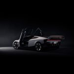 Tesla Roadster schuin van achteren in een donkere studio, met beide deuren omhoog geopend, uitgeklapte spoiler en rode lichtbalk.